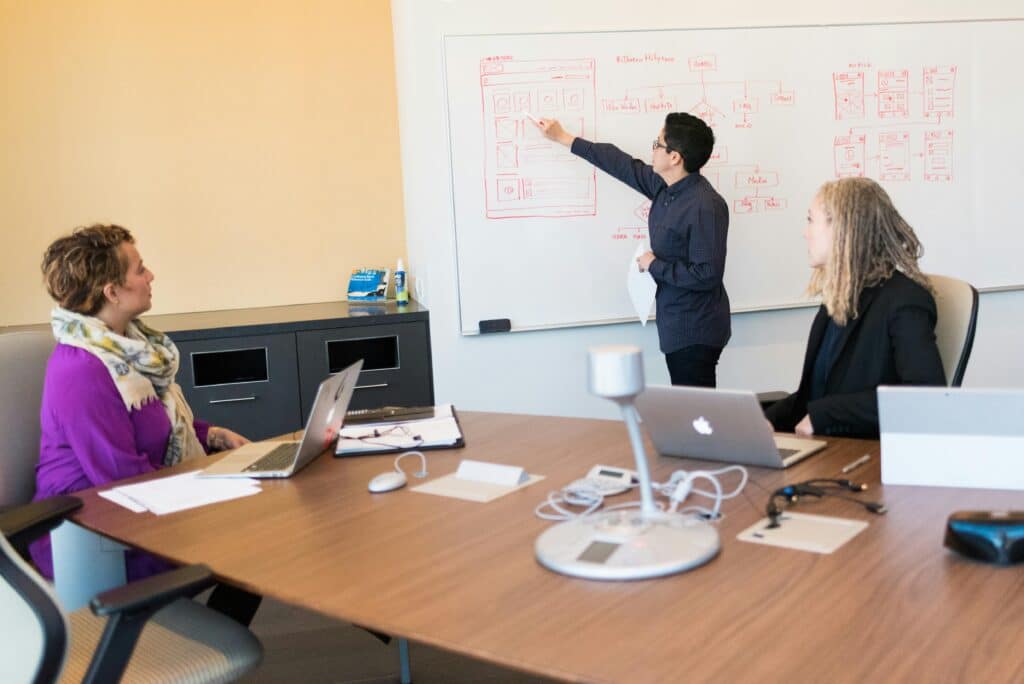UX designer presenting a website layout on a whiteboard to a team during a design session.